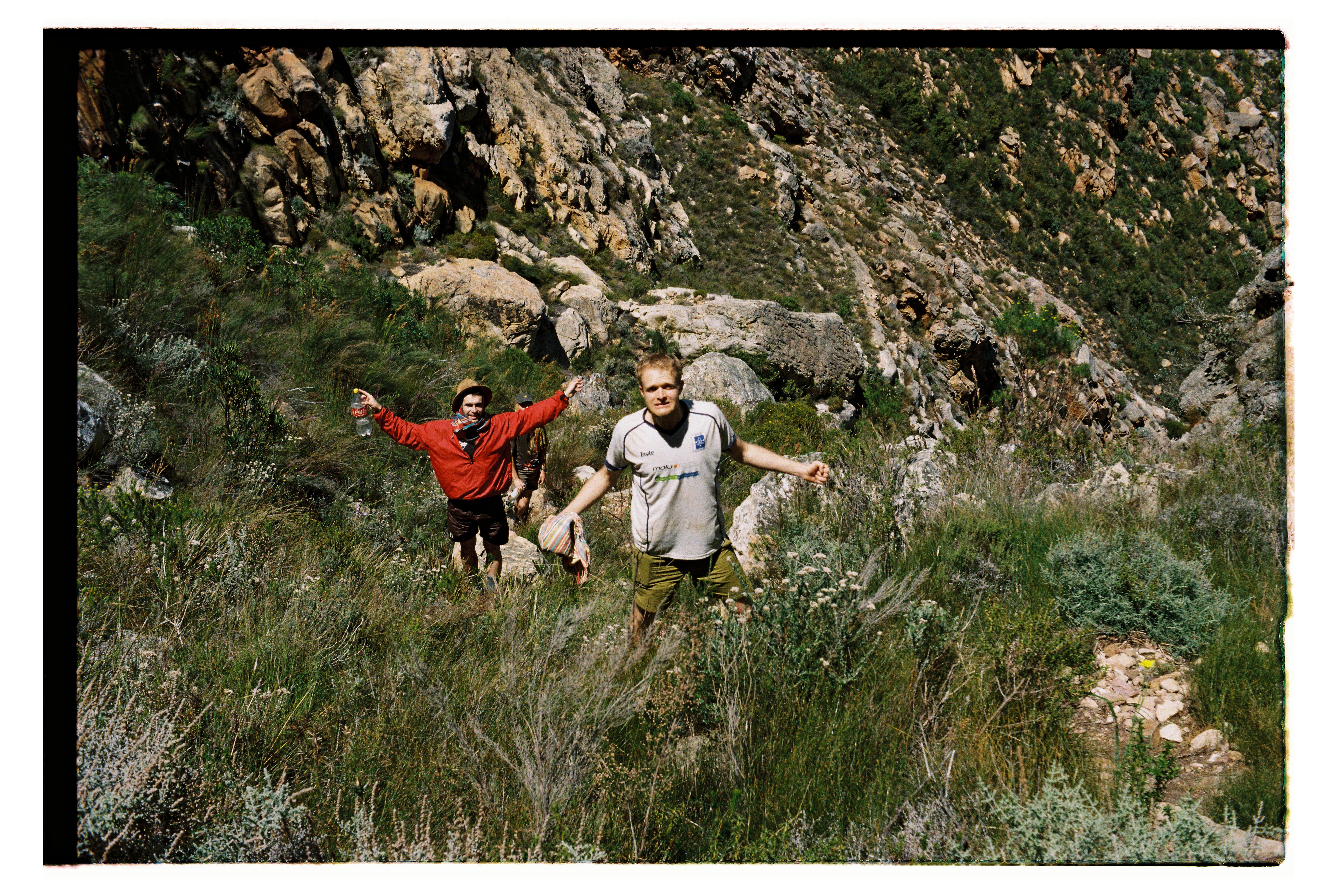 Two men pose for camera standing in a valley.