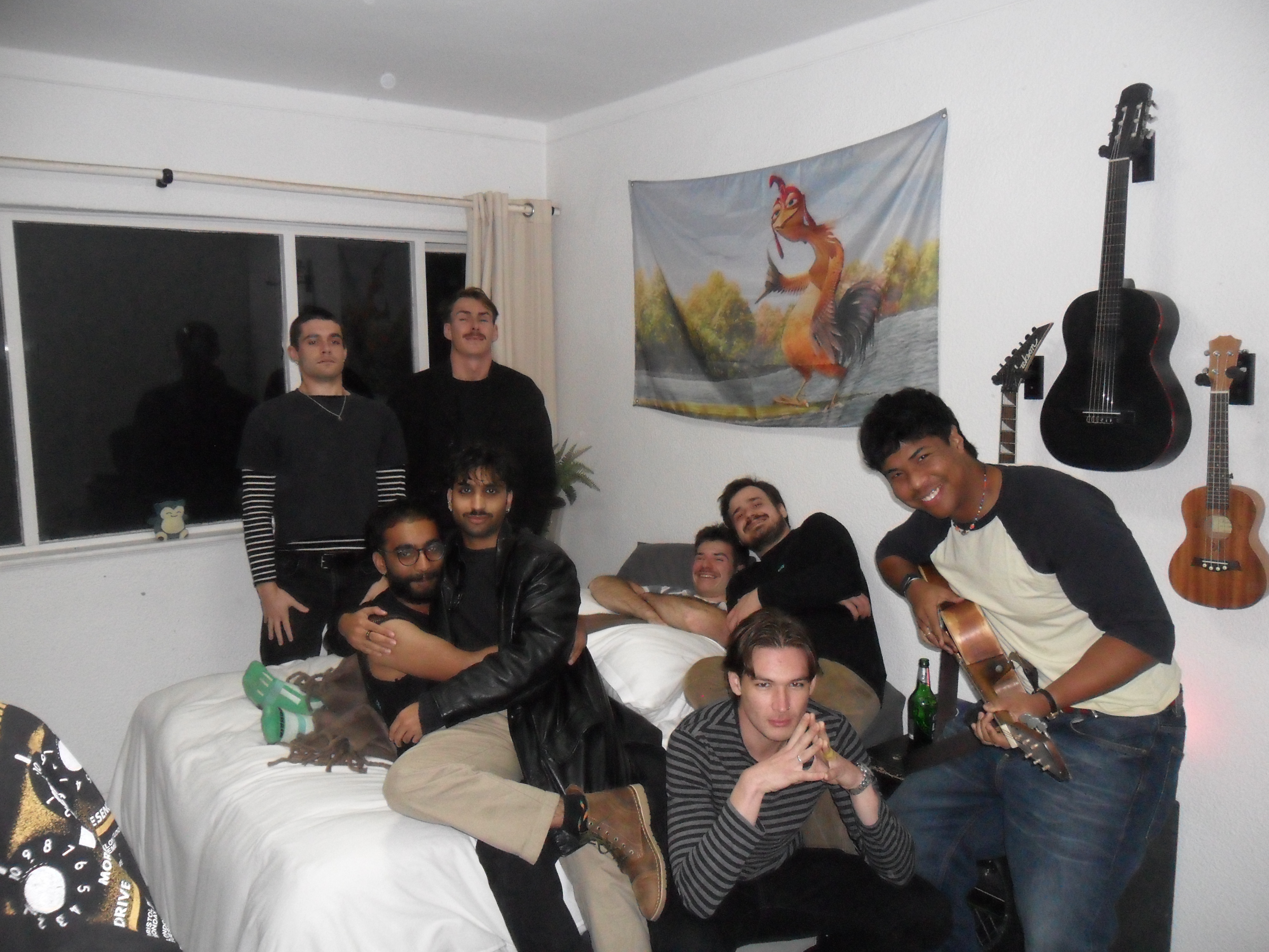 A group photo of 8 people around and on a bed.