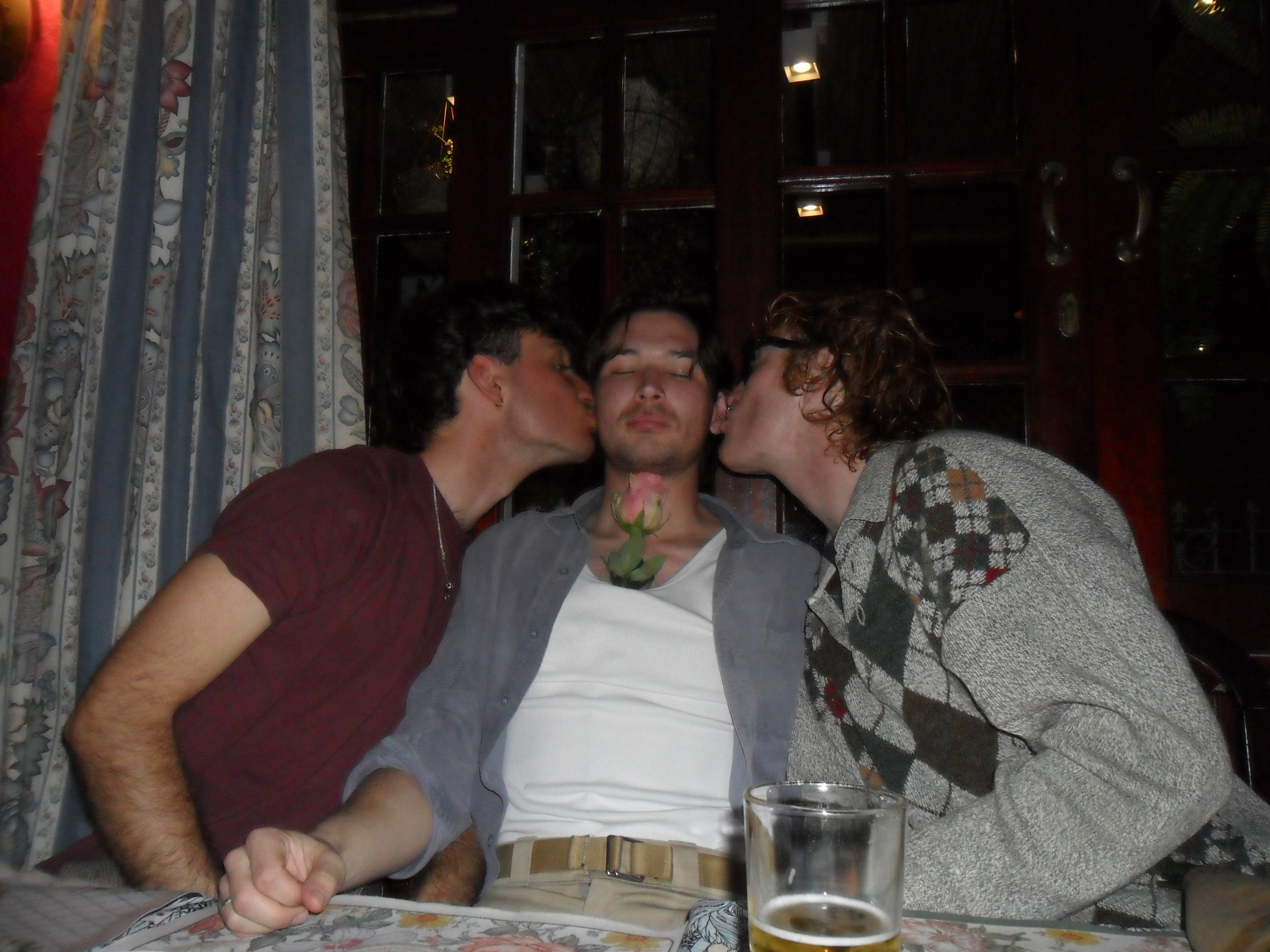 Two men kiss a third man on either cheek